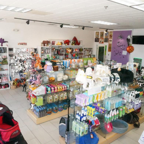 A brightly lit pet store featuring neatly arranged shelves filled with pet supplies, toys, and grooming products. The atmosphere is vibrant and welcoming.