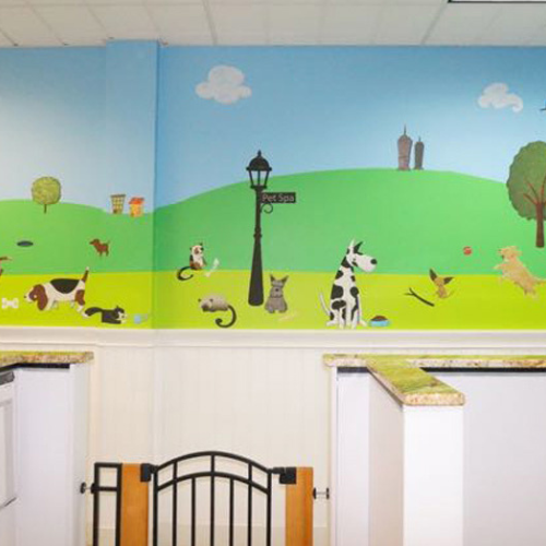 Colorful mural in an animal-themed room depicts playful cats and dogs on a grassy hill under a blue sky. A lamp post and trees add charm.