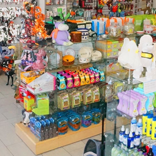 A pet supply store display with colorful products, including toys, pet food, grooming items, and plush animals. Bright and inviting atmosphere.